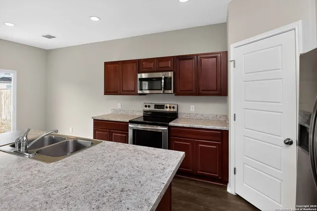 a kitchen with granite countertop wooden cabinets and a stove top oven