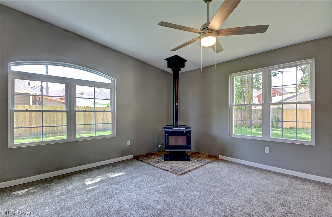 14507 Glencliffe Road Cleveland, OH 44111 - Photo 18 of 31 Unfurnished living room with carpet floors, ceiling fan, and a wood stove