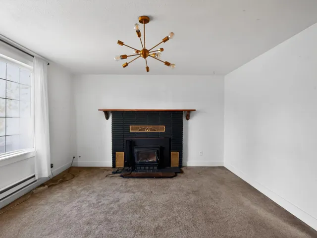 a view of an empty room with a fireplace and a window