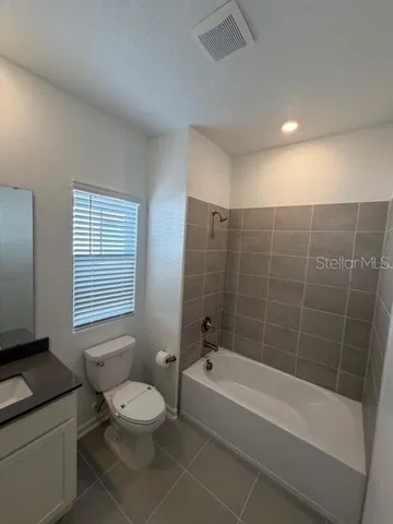 a bathroom with a granite countertop toilet a sink a mirror and shower