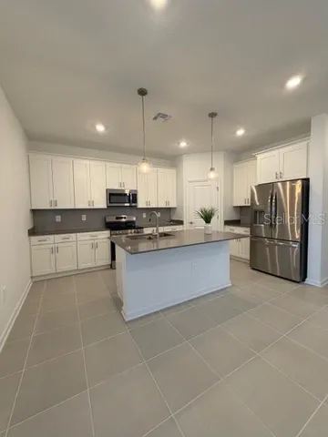 a large kitchen with granite countertop a large counter top stainless steel appliances and cabinets