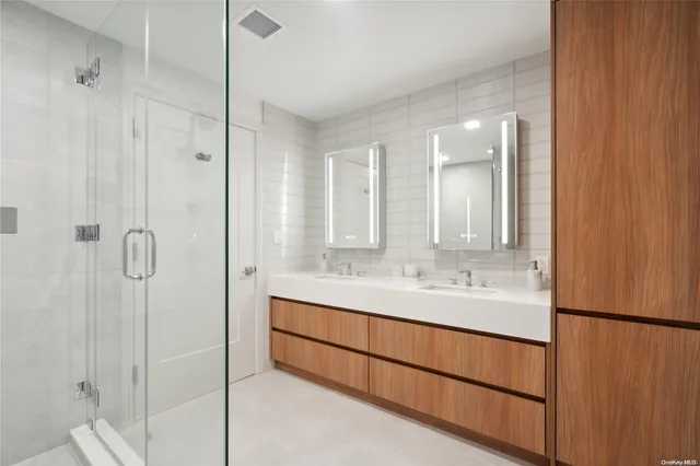 a bathroom with a double vanity sink a mirror and shower