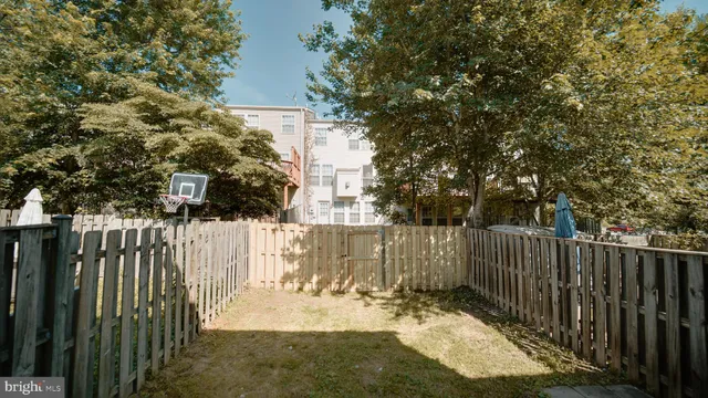 a view of a backyard with wooden fence and a tree