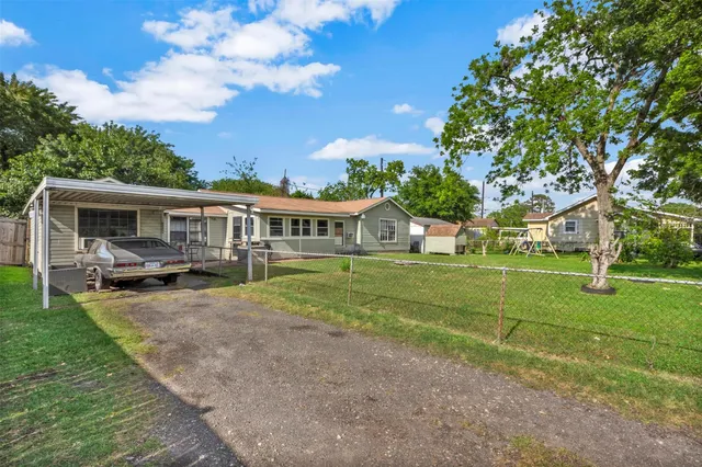 a view of house with a big yard and large trees
