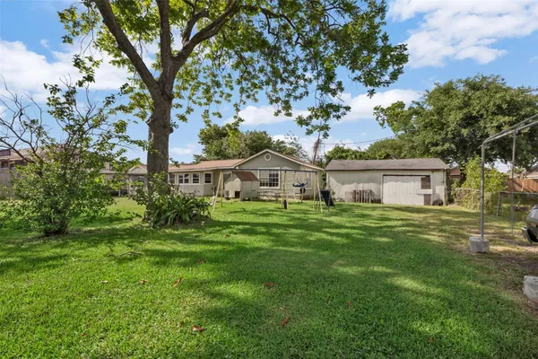 a view of a big house with a big yard and large trees