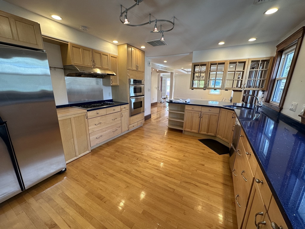 a large kitchen with stainless steel appliances a large counter top a refrigerator and a television