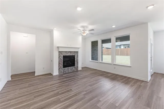 a view of an empty room with wooden floor fireplace and a window