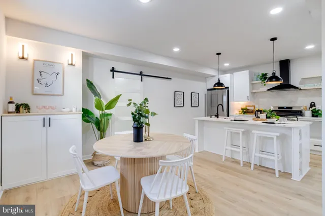 a kitchen with stainless steel appliances a dining table chairs and wooden floor