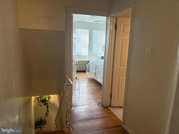 a view of a hallway with wooden floor and a bedroom
