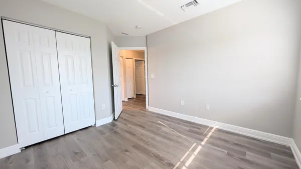 a view of an empty room with closet and wooden floor