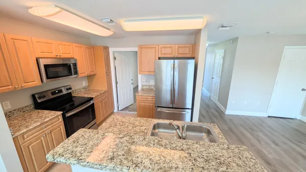 a kitchen with stainless steel appliances kitchen island granite countertop a refrigerator stove and sink