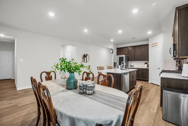 a dining room with furniture a potted plant and kitchen view