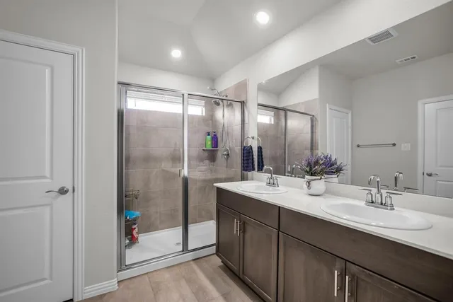 a bathroom with a double vanity sink mirror and shower