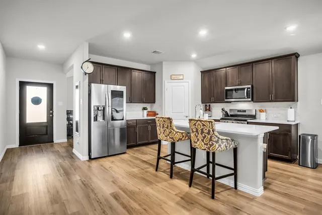 a kitchen with stainless steel appliances a dining table chairs stove refrigerator and cabinets