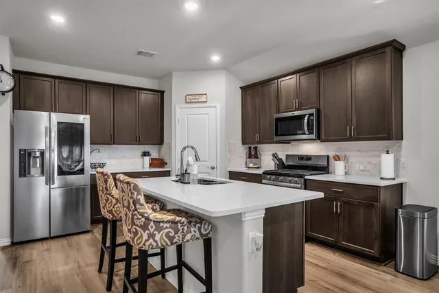 a kitchen with a stove a sink a microwave a refrigerator and cabinets
