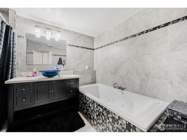 a bathroom with a sink vanity granite tub shower and a mirror