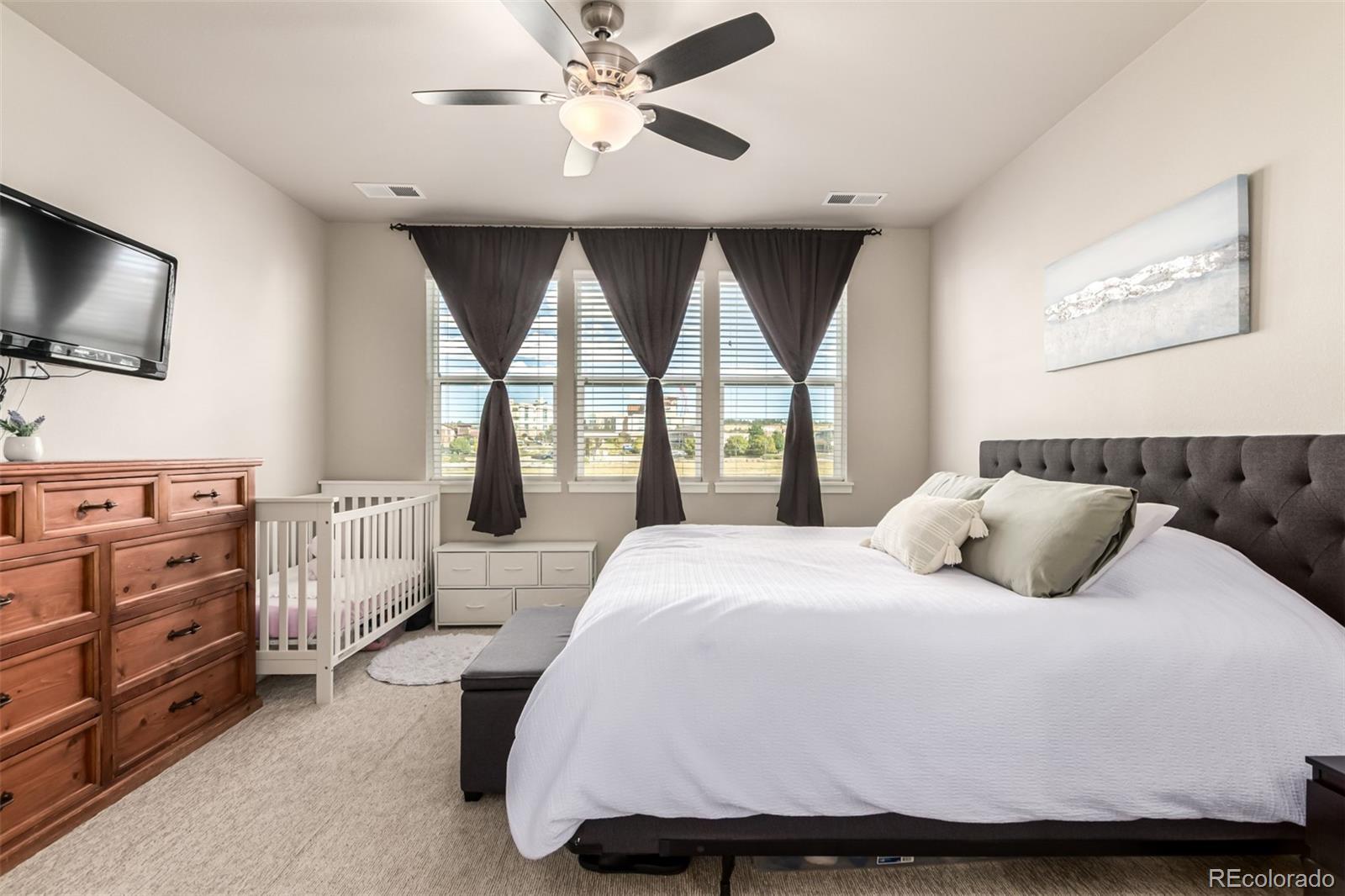 9287 Twenty Mile Road, Unit 204 Parker, CO 80134 - Photo 12 of 30 a bedroom with a large bed and a flat tv screen on dresser
