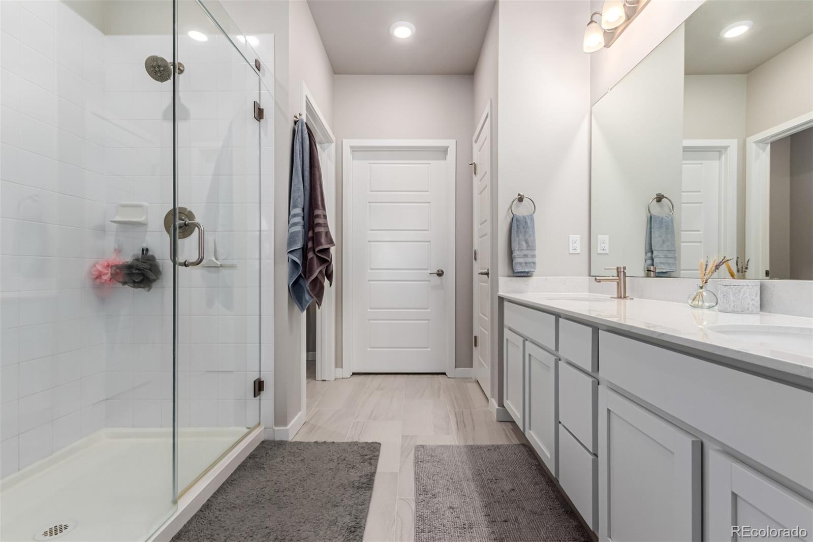9287 Twenty Mile Road, Unit 204 Parker, CO 80134 - Photo 14 of 30 a bathroom with a double vanity sink a large mirror and shower