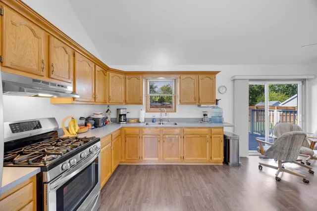 a kitchen with a stove a sink and wooden floor