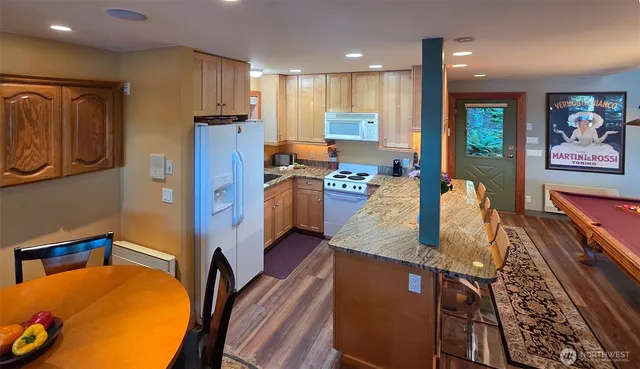a kitchen with stainless steel appliances granite countertop a refrigerator a stove top oven and a dining table