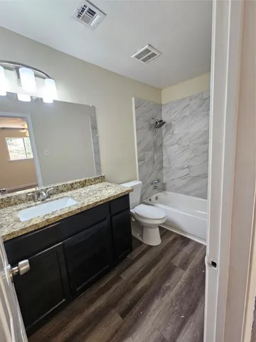 a bathroom with a granite countertop toilet sink and mirror