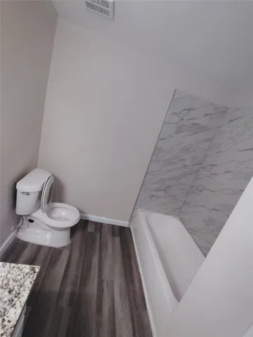 a bathroom with a granite countertop sink and a toilet