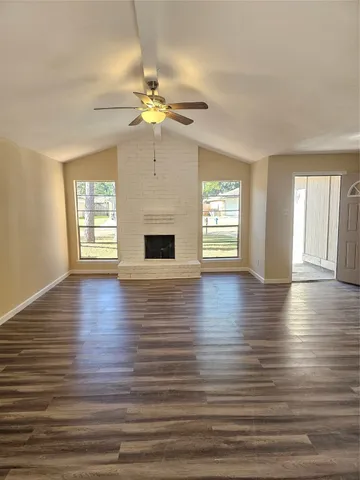 an empty room with wooden floor chandelier fan and windows