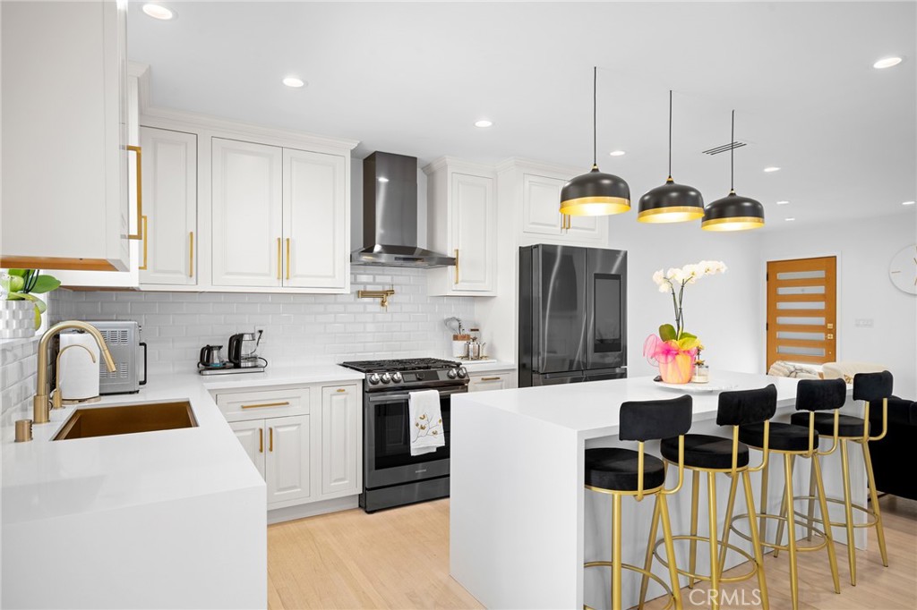 6625 Shadygrove Street Tujunga, CA 91042 - Photo 12 of 25 a kitchen with stainless steel appliances kitchen island granite countertop a stove a sink a dining table and chairs with white cabinets