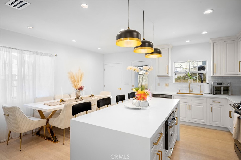 6625 Shadygrove Street Tujunga, CA 91042 - Photo 9 of 25 a kitchen with stainless steel appliances a table chairs and white cabinets
