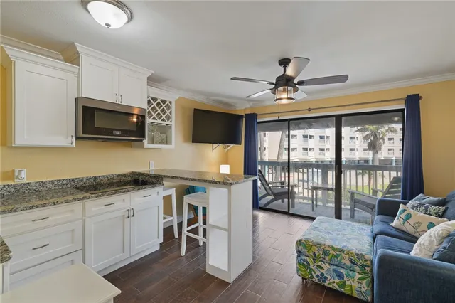 a kitchen with granite countertop a stove top oven a sink a dining table and chairs with wooden floor