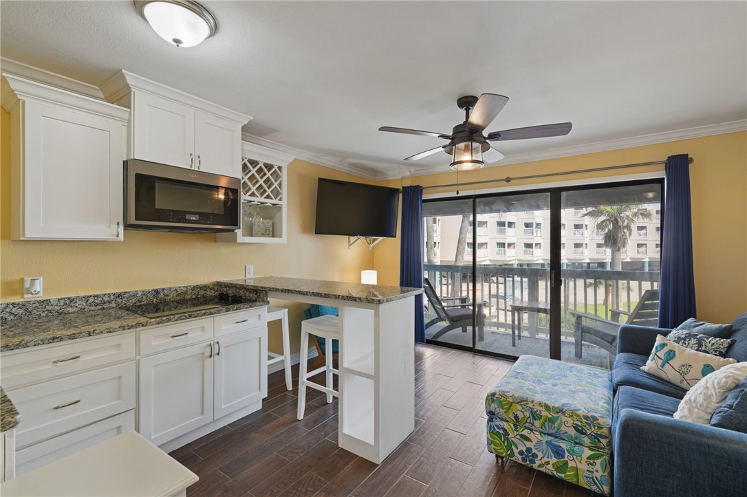 3938 Surfside Boulevard, Unit 1139 Corpus Christi, TX 78402 - Photo 6 of 14 a kitchen with granite countertop a stove top oven a sink a dining table and chairs with wooden floor