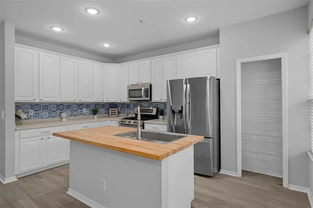 a kitchen with kitchen island a counter top space a sink stainless steel appliances and cabinets