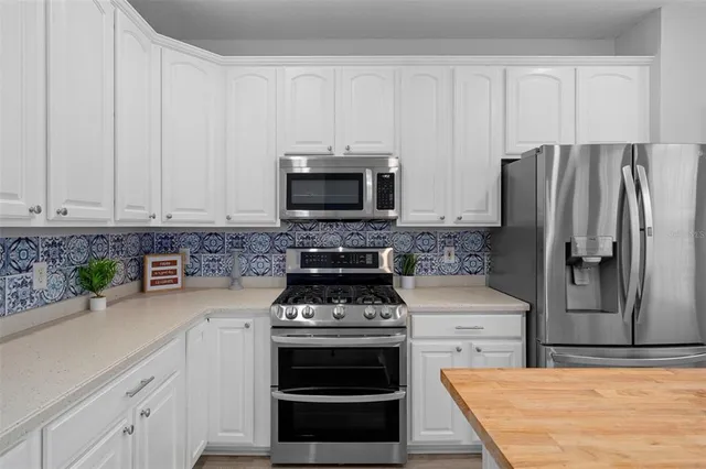a kitchen with a refrigerator and white cabinets