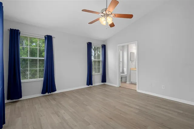 an empty room with wooden floor and a ceiling fan