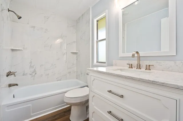 a bathroom with a granite countertop toilet a sink and a bathtub