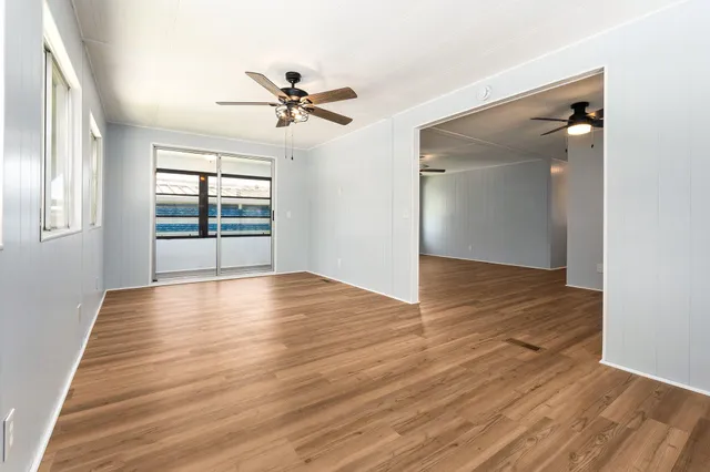 a view of empty room with wooden floor and fan