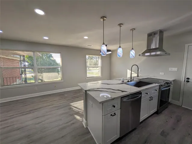 a kitchen with stainless steel appliances granite countertop a sink a stove and a wooden floors