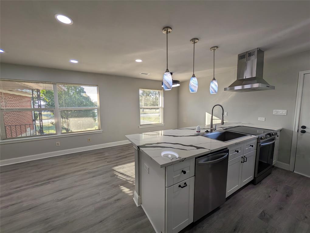 a kitchen with stainless steel appliances granite countertop a sink a stove and a wooden floors