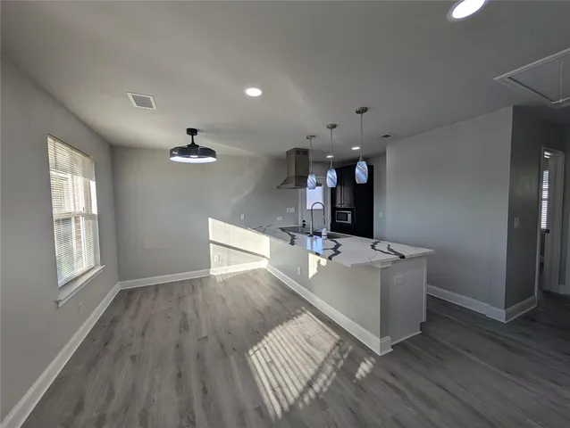 a living room with kitchen island granite countertop wooden floor and ceiling fan