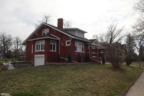 a view of a yard in front of a house with large trees