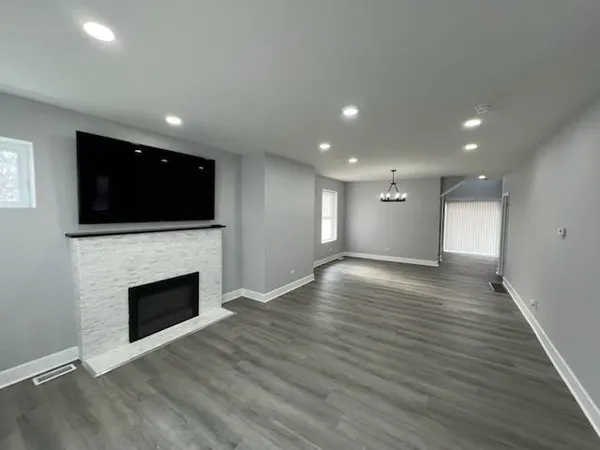 a view of an empty room with wooden floor and a fireplace