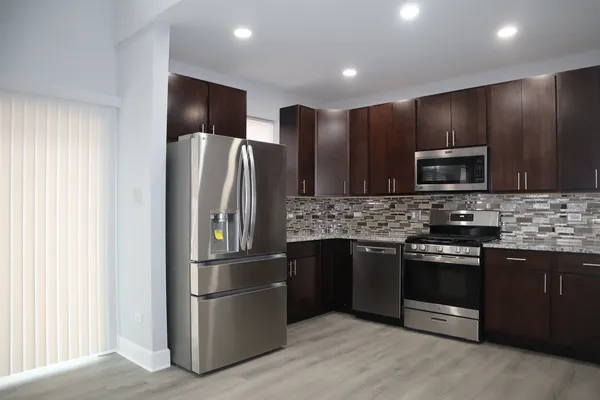 a kitchen with stainless steel appliances granite countertop a refrigerator and a stove top oven