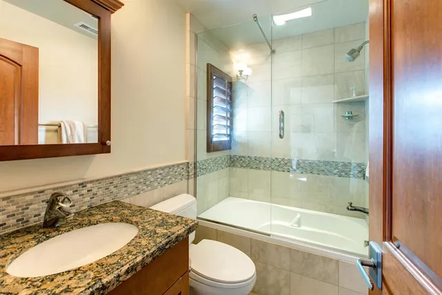 a bathroom with a granite countertop toilet a sink and a bathtub