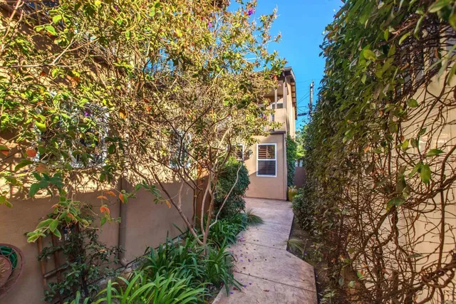 a pathway of a house with yard and tree in front of it