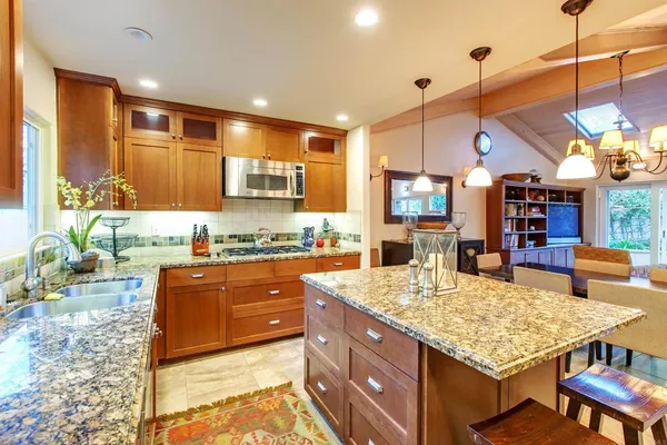 a large kitchen with kitchen island a large counter top space a sink stainless steel appliances and cabinets