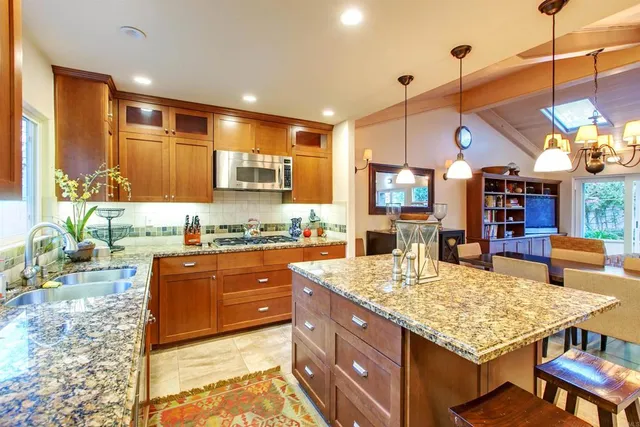 a large kitchen with kitchen island a large counter top space a sink stainless steel appliances and cabinets