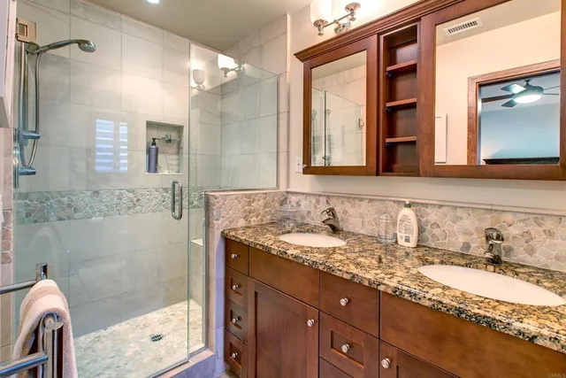 a bathroom with a granite countertop sink mirror and shower