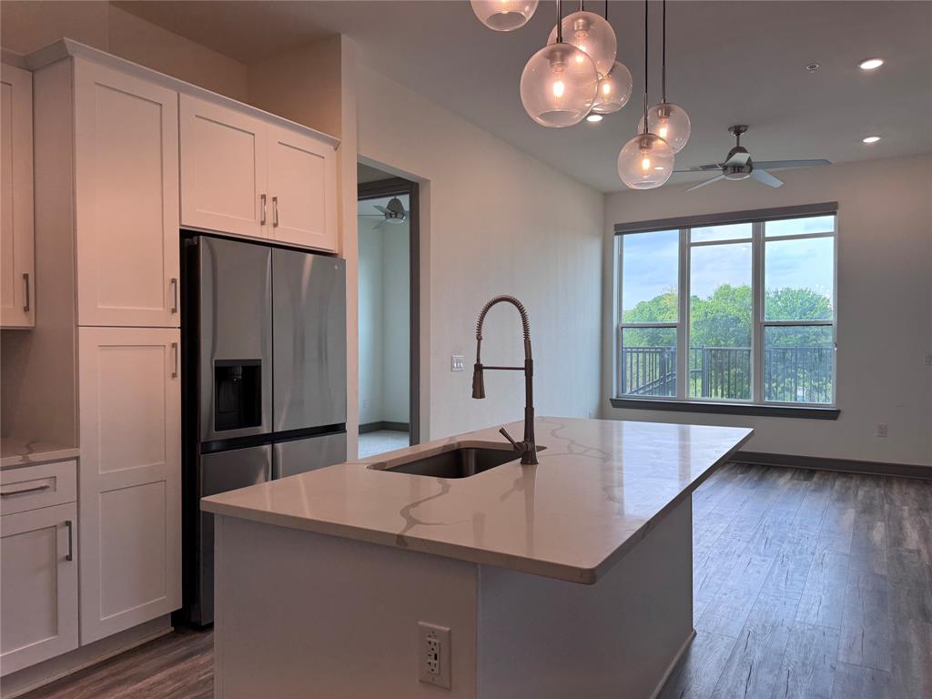2700 Old Denton Road, Unit 1030 Carrollton, TX 75007 - Photo 3 of 28 a kitchen with stainless steel appliances a microwave a stove and a refrigerator with wooden floor