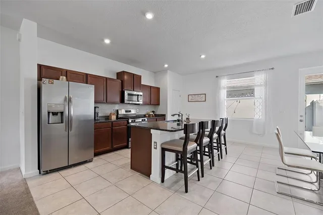 a kitchen with stainless steel appliances kitchen island granite countertop a stove a sink a dining table and chairs