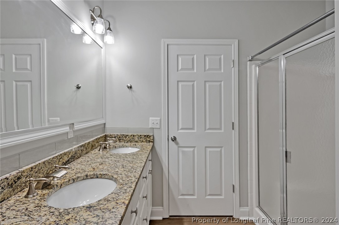 3713 Glenn Road Parkton, NC 28371 - Photo 13 of 17 a bathroom with a granite countertop sink a mirror and shower